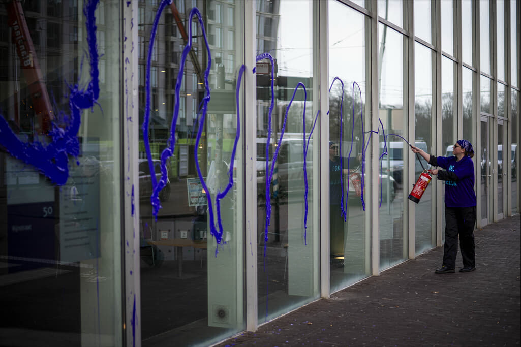 Rebel die met een brandblusser gevuld met paarse verf ramen bespuit.